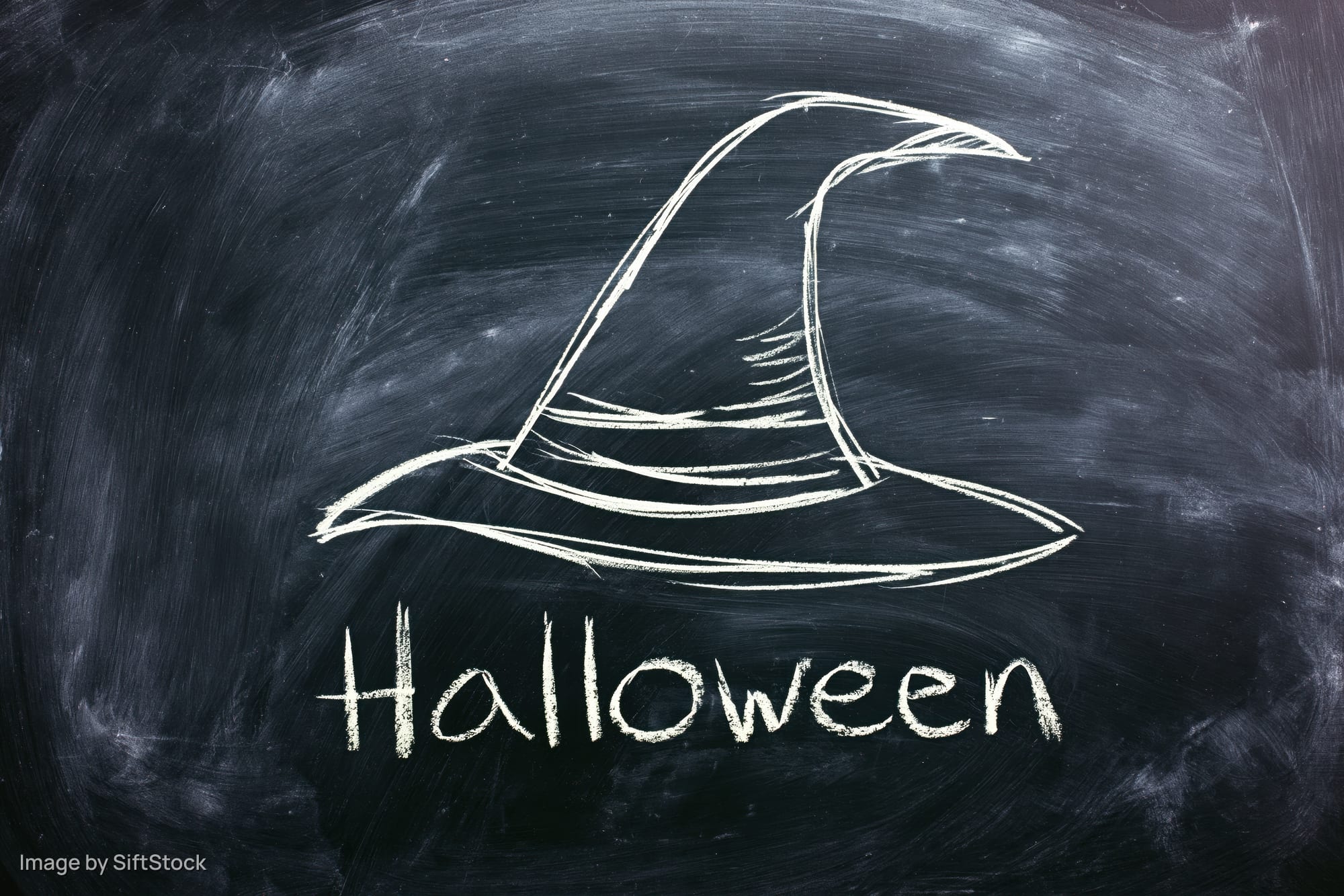 Chalk drawing of a witch hat and the word halloween on a blackboard