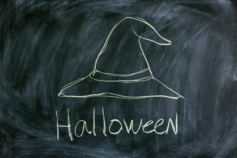Chalk drawing of a witch hat and the word halloween on a blackboard