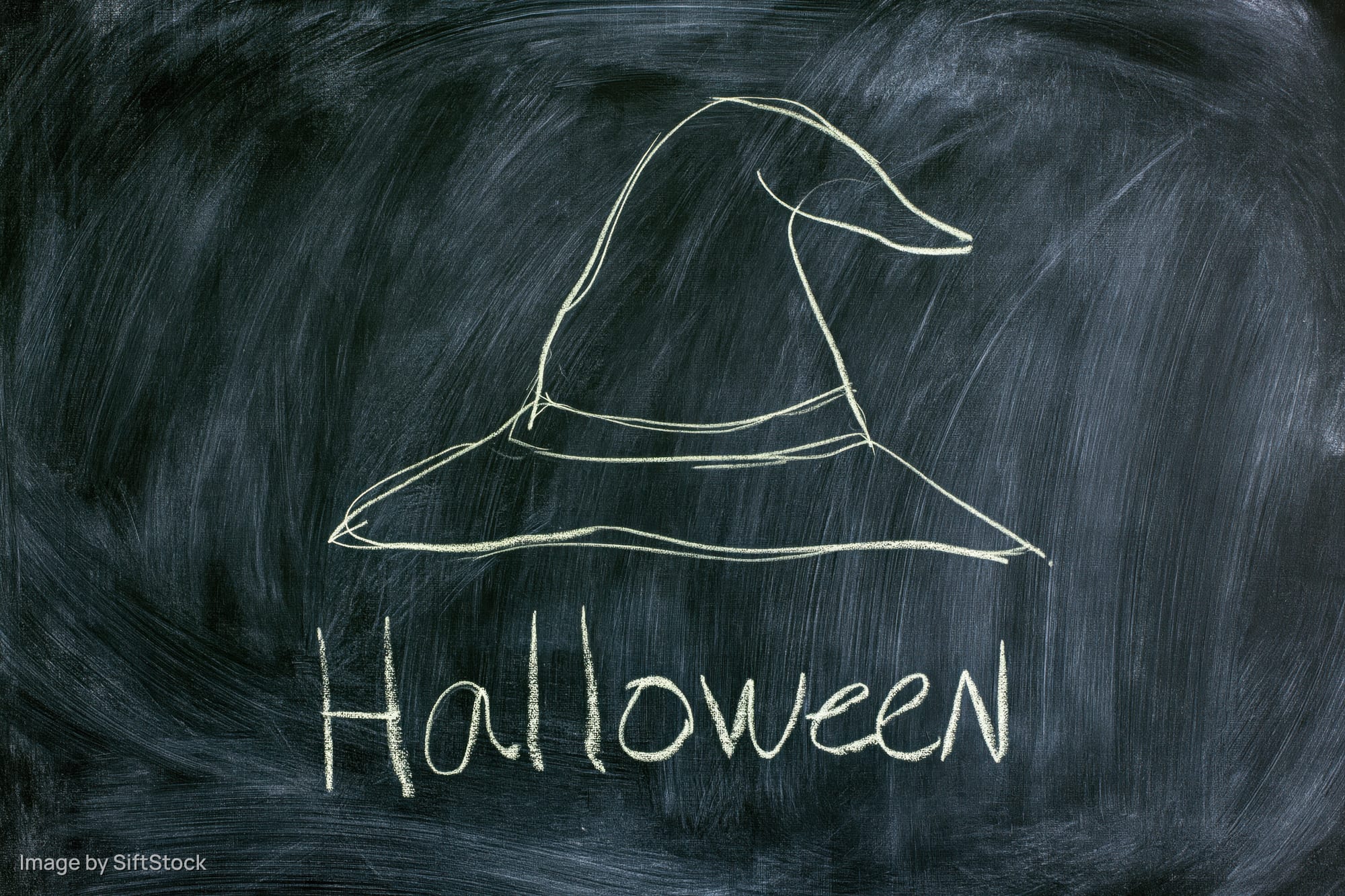 Chalk drawing of a witch hat and the word halloween on a blackboard