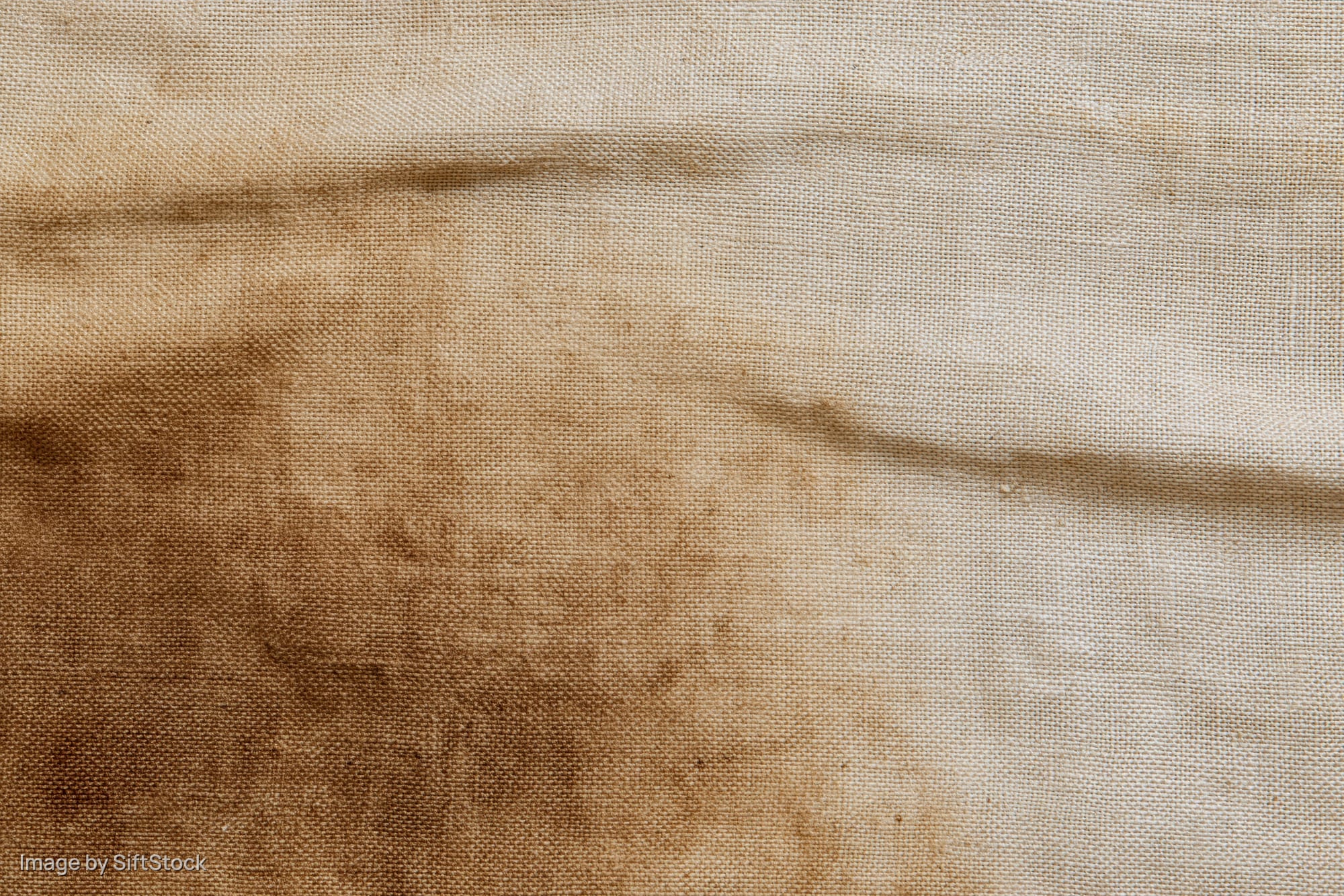 Close-up of aged linen fabric with stains and creases filling the frame