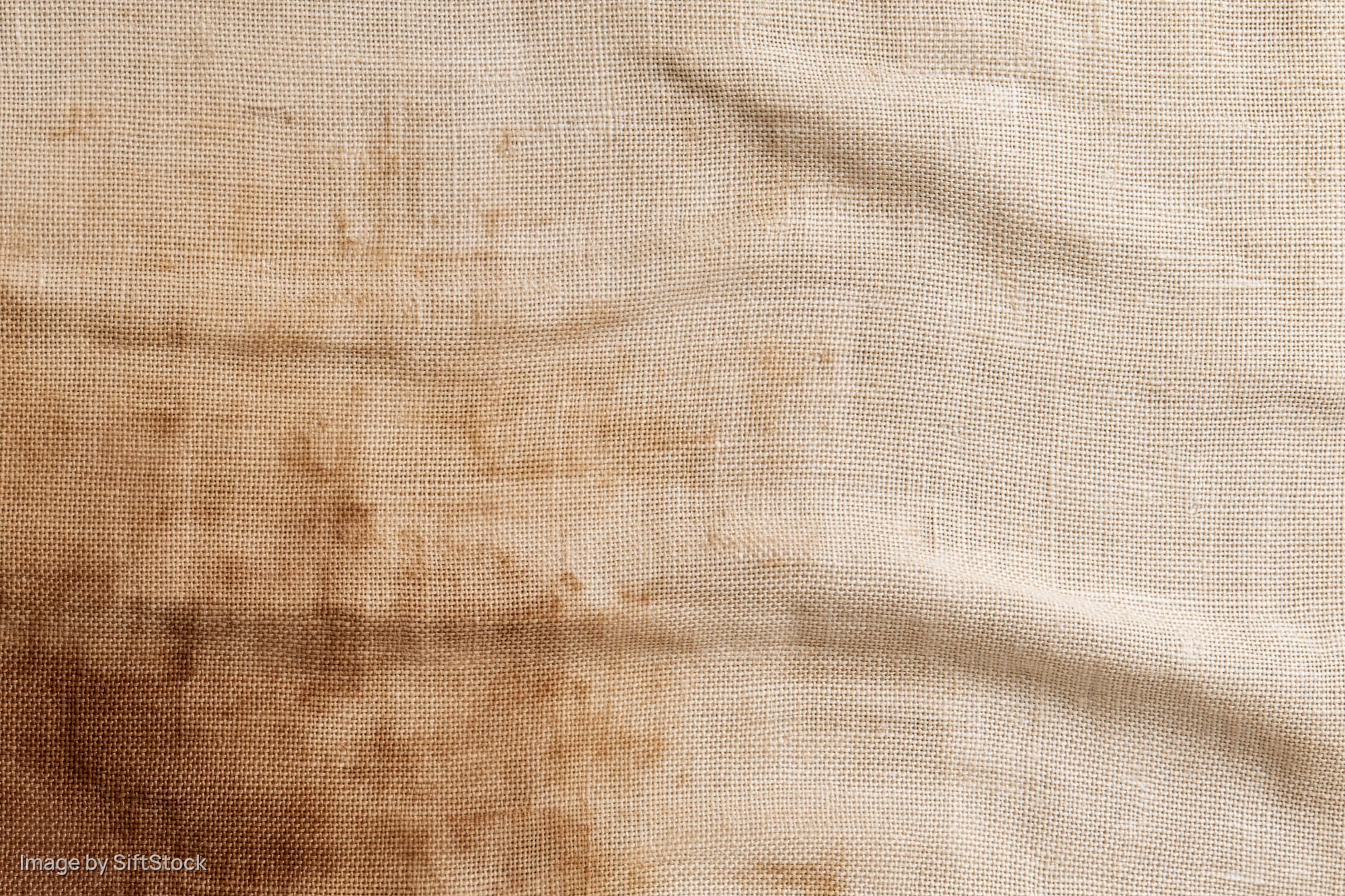 Close-up of aged linen fabric with stains and creases filling the frame