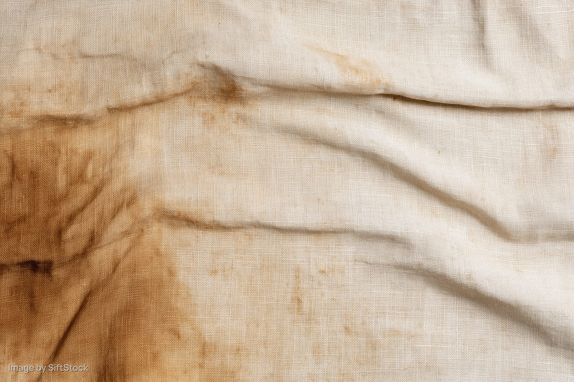 Close-up of aged linen fabric with stains and wrinkles filling the frame