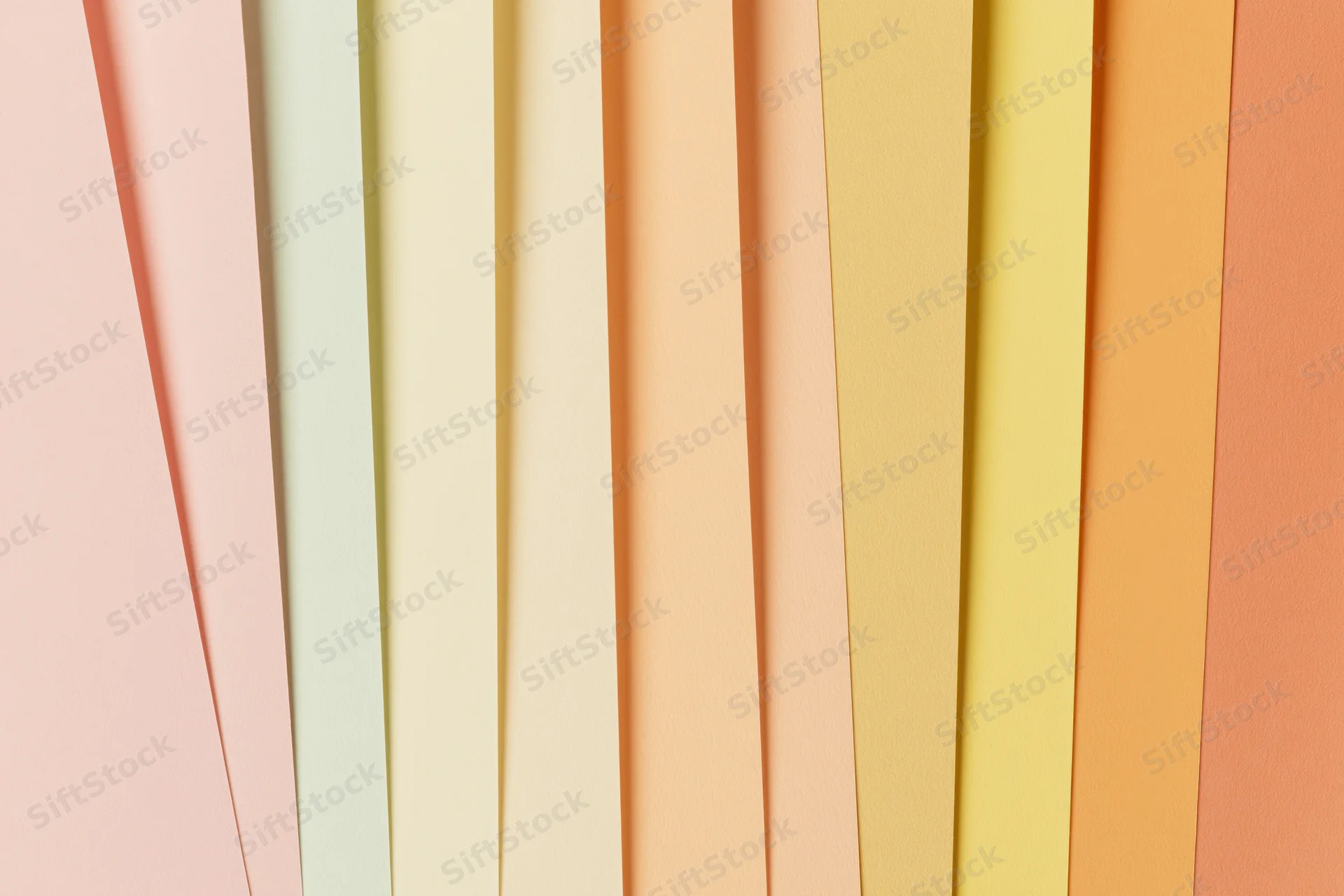 Overlapping sheets of pastel colored paper fanned out in a flat lay arrangement