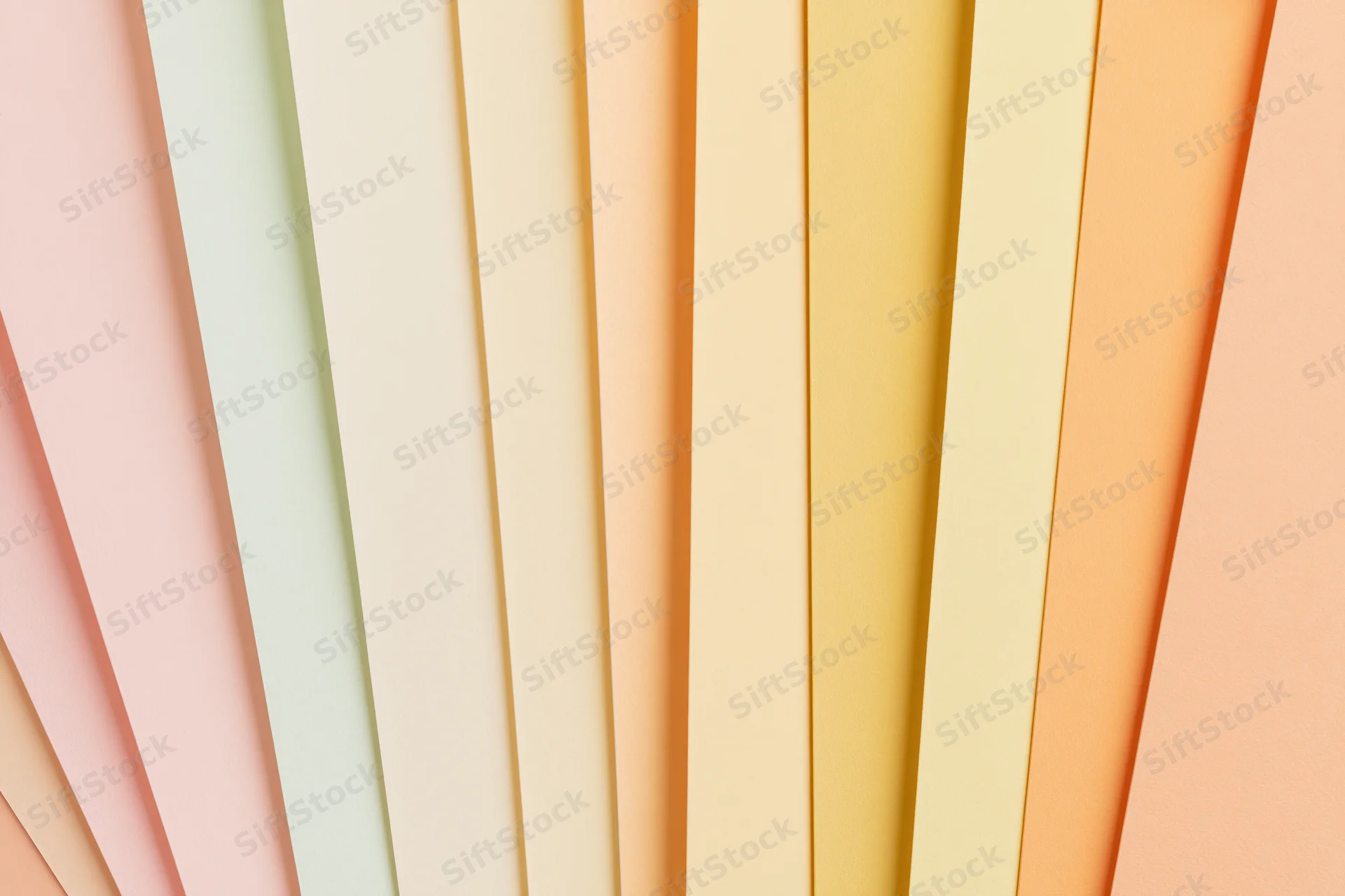 Fanned sheets of pastel colored paper arranged in flat lay composition