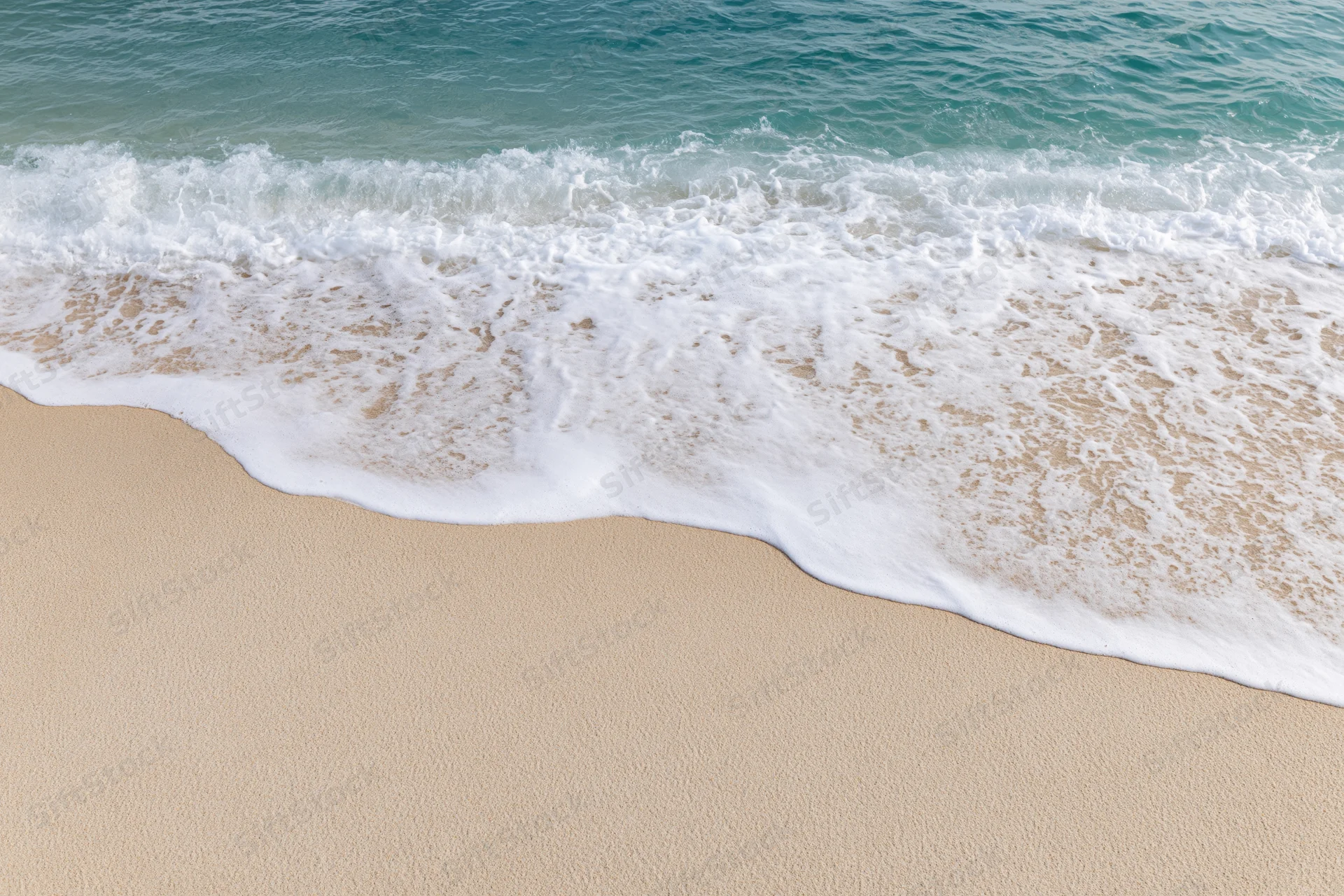 Gentle ocean wave washing onto clean sandy beach