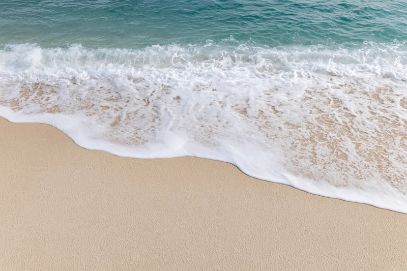 Gentle ocean wave washing onto clean sandy beach