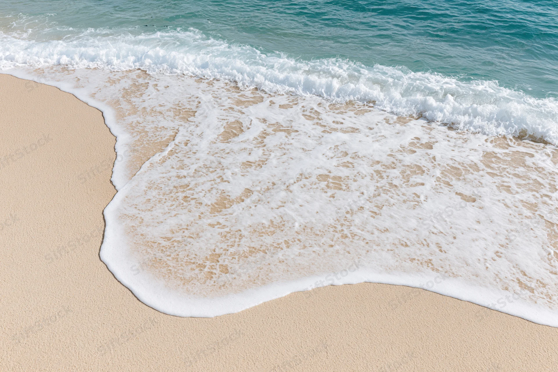 Gentle ocean wave washing onto clean sandy beach