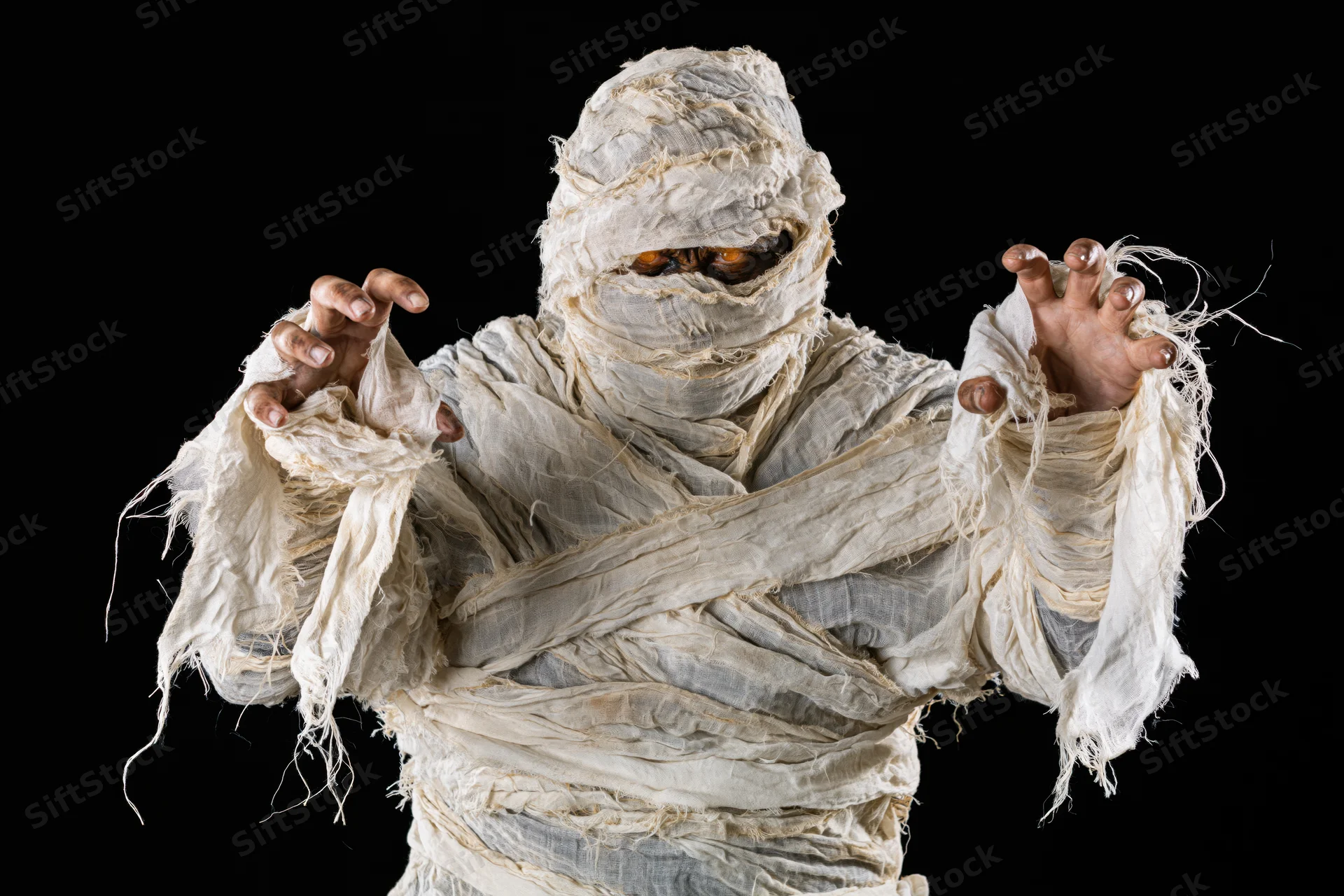 Mummy in white bandages reaching forward against black background