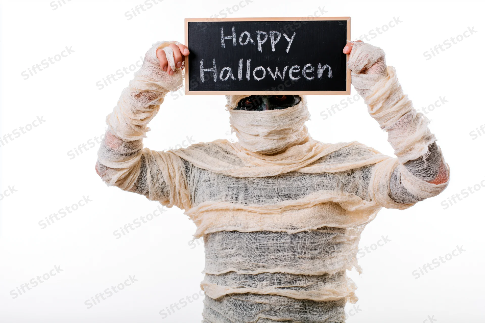 Mummy in bandages holding chalkboard sign with happy halloween text against white background