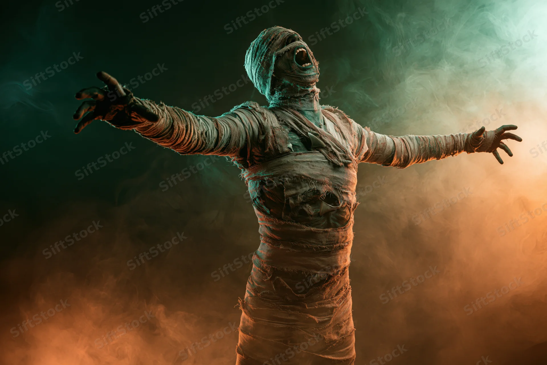 Mummy in full costume screaming with arms outstretched in smoky dark atmosphere