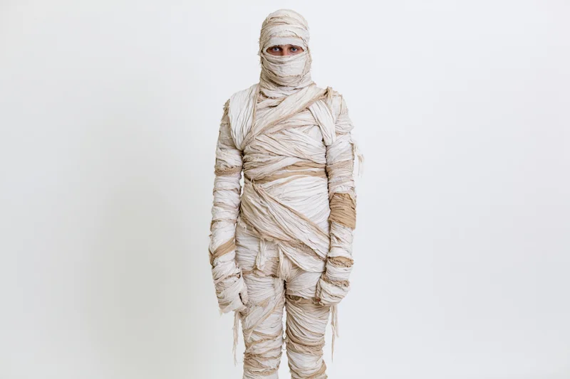 Person in full-body mummy costume standing upright against white background