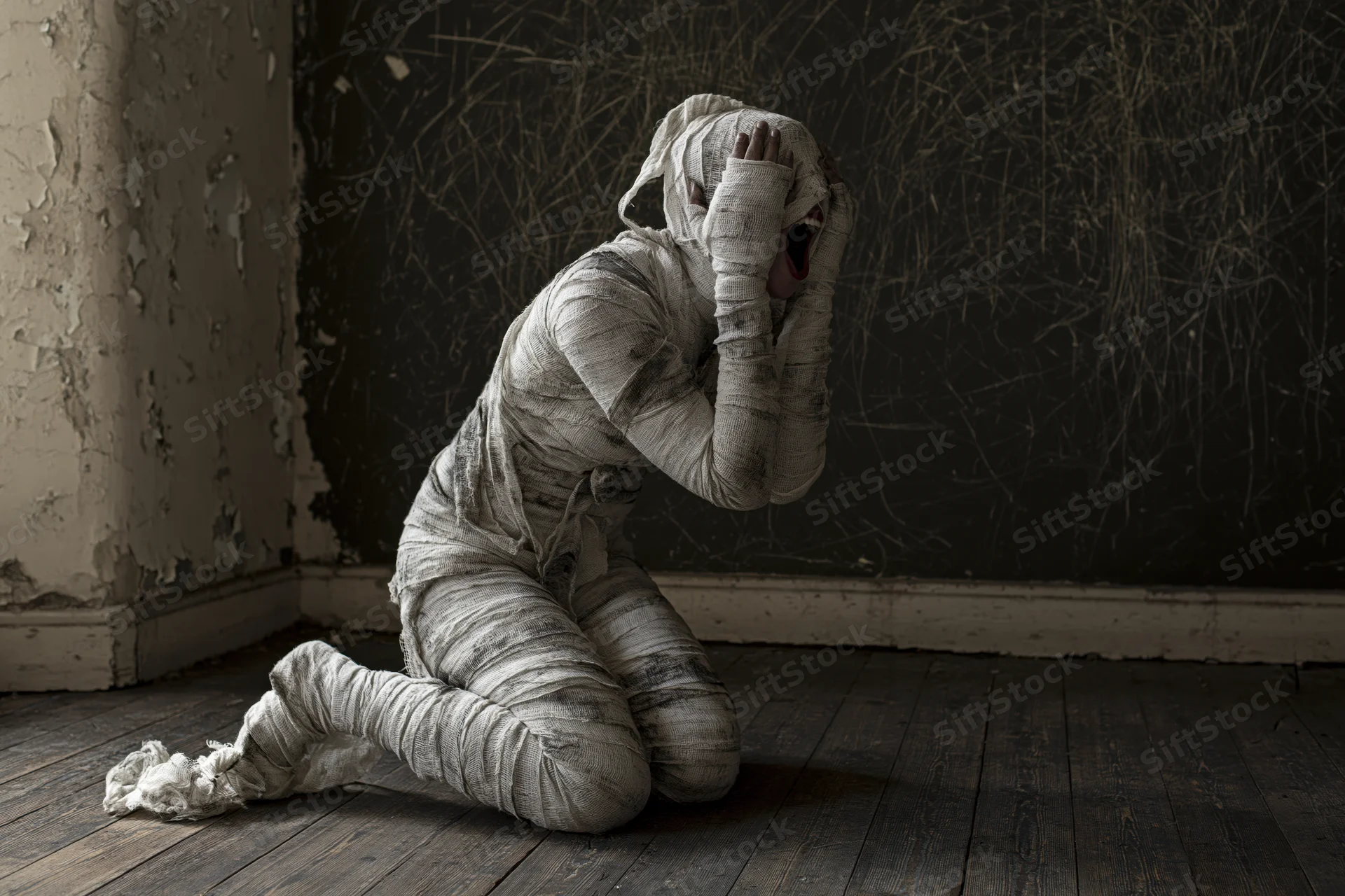 Mummy wrapped in dirty bandages kneeling and screaming in a dark, decaying room