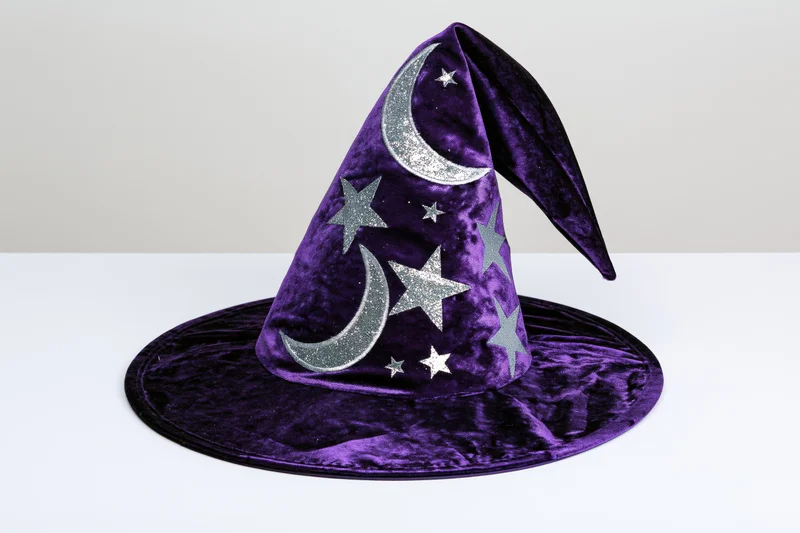 Purple velvet wizard hat with silver glitter moons and stars on white surface