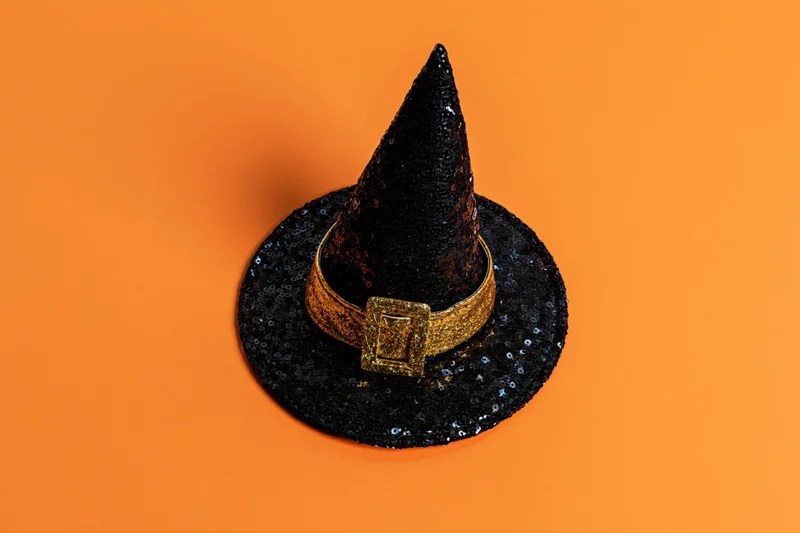 Black sequined witch hat with gold glitter buckle on orange background