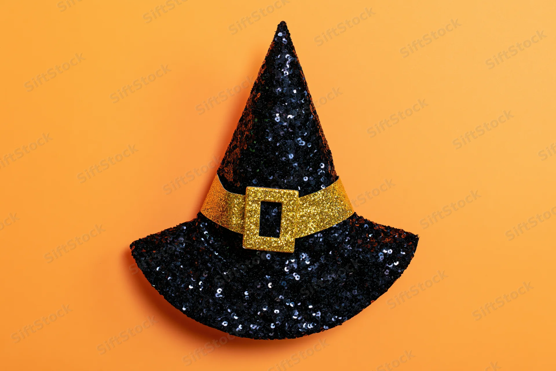 Black sequined witch hat with gold glitter buckle on orange background