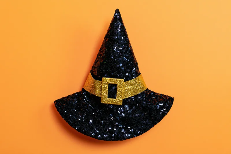 Black sequined witch hat with gold glitter buckle on orange background