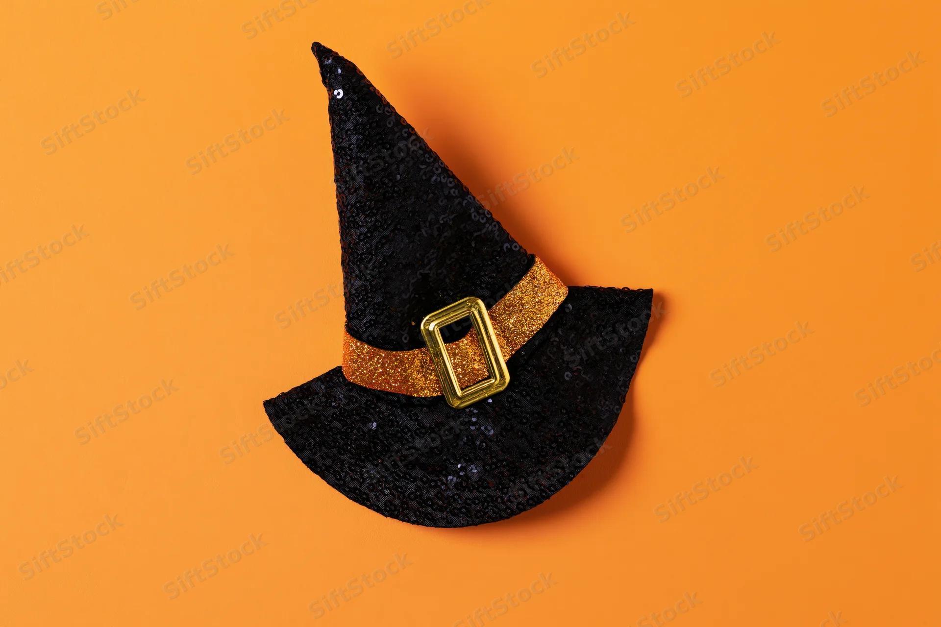 Black sequined witch hat with gold glitter buckle on orange background