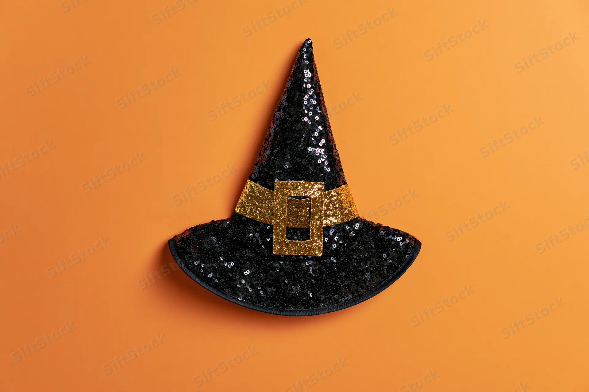 Black sequined witch hat with gold glitter buckle on orange background