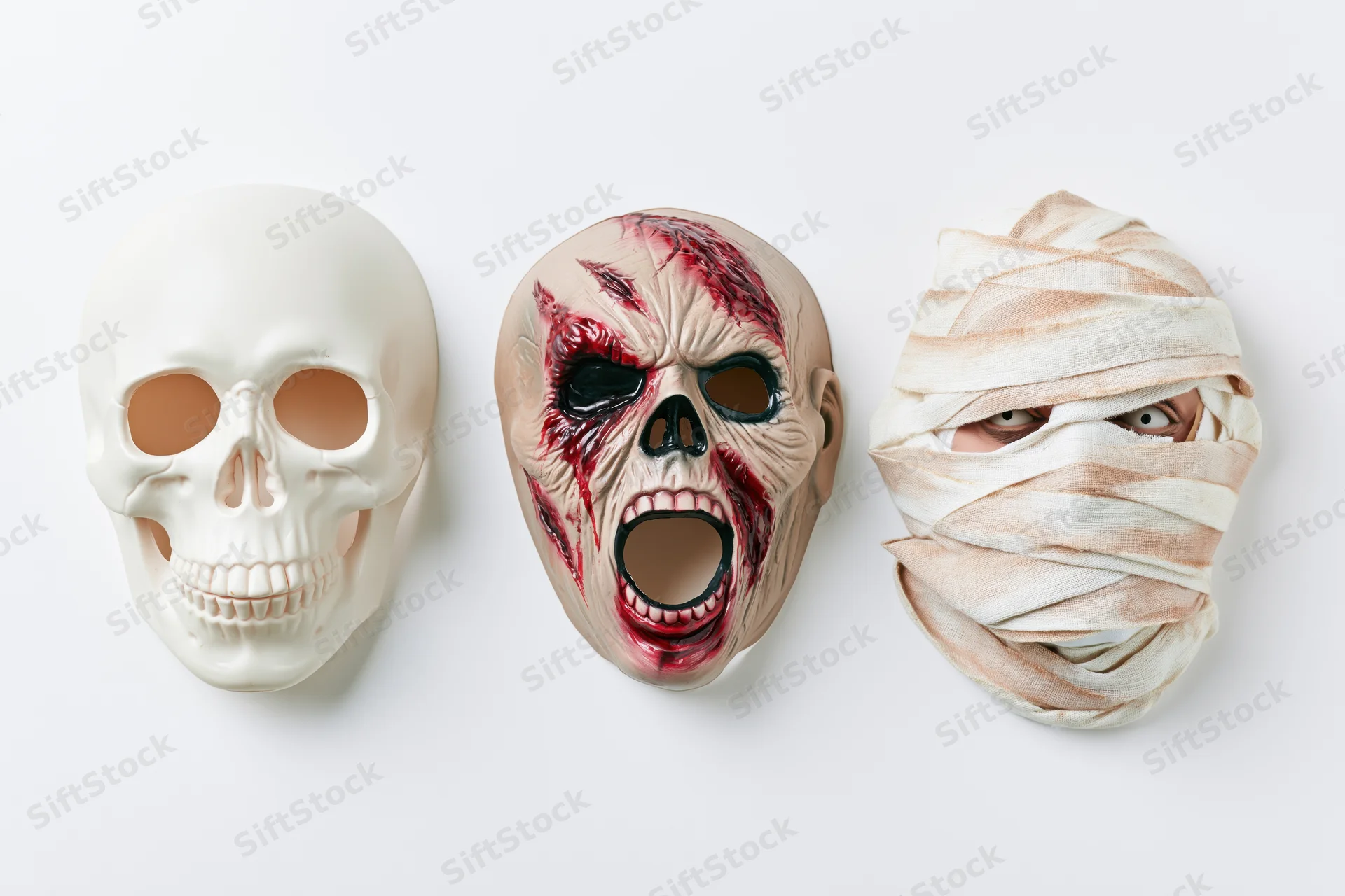 Three halloween rubber masks — skull, zombie, and mummy — arranged side by side on white background