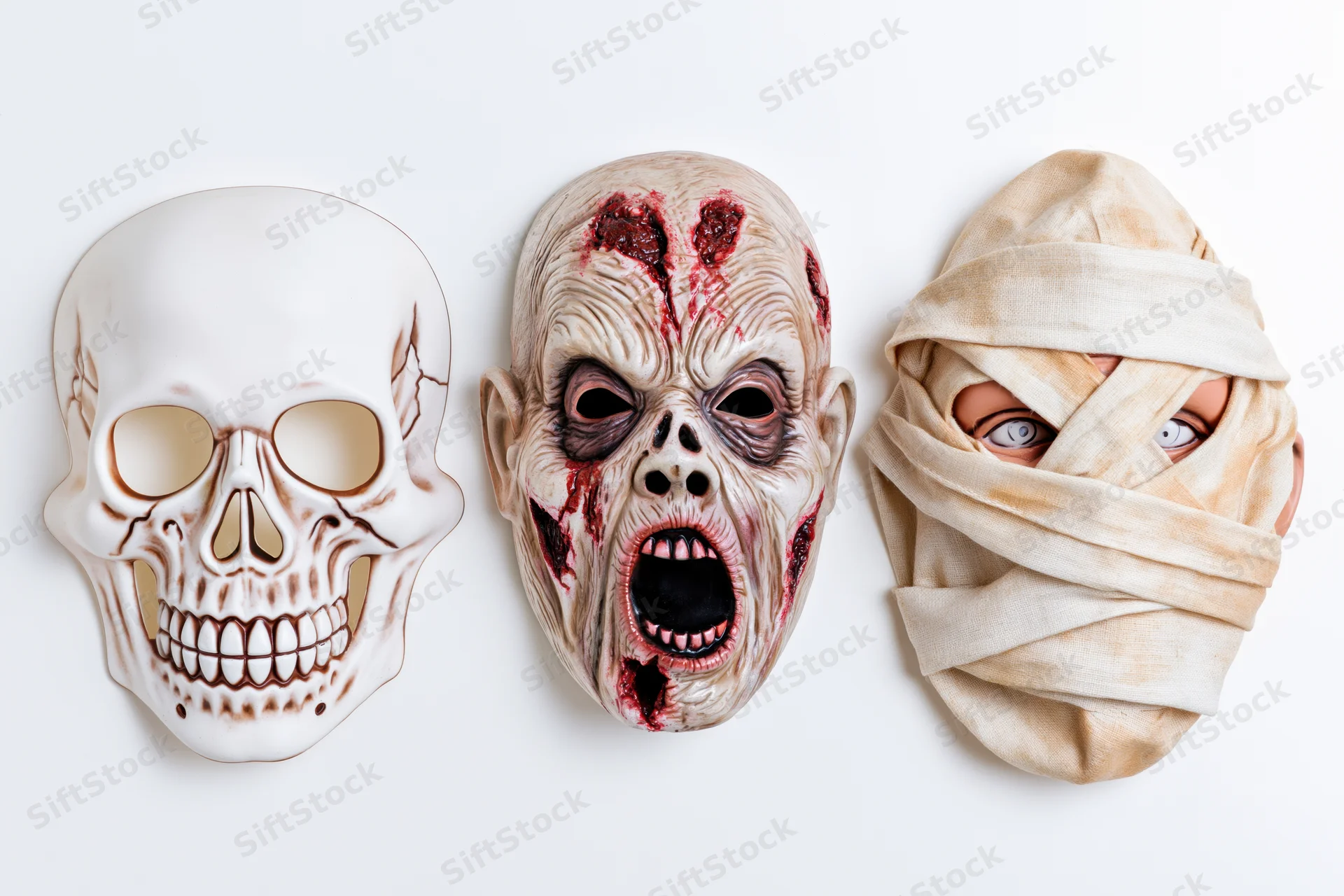 Three halloween rubber masks — skull, zombie, and mummy — arranged side by side on white background