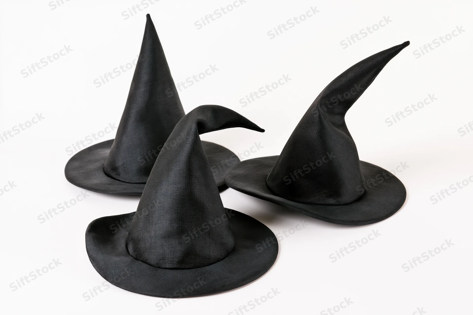 Three small black fabric witch hats arranged in a loose cluster on a white background