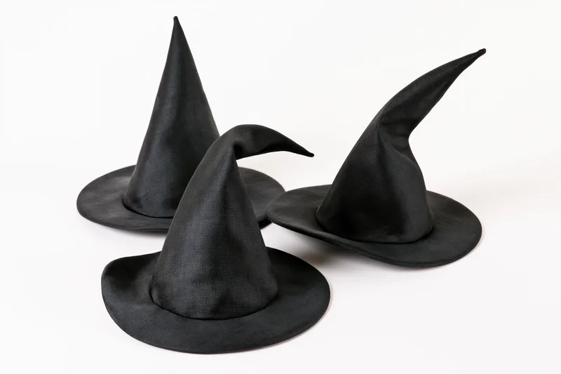 Three small black fabric witch hats arranged in a loose cluster on a white background
