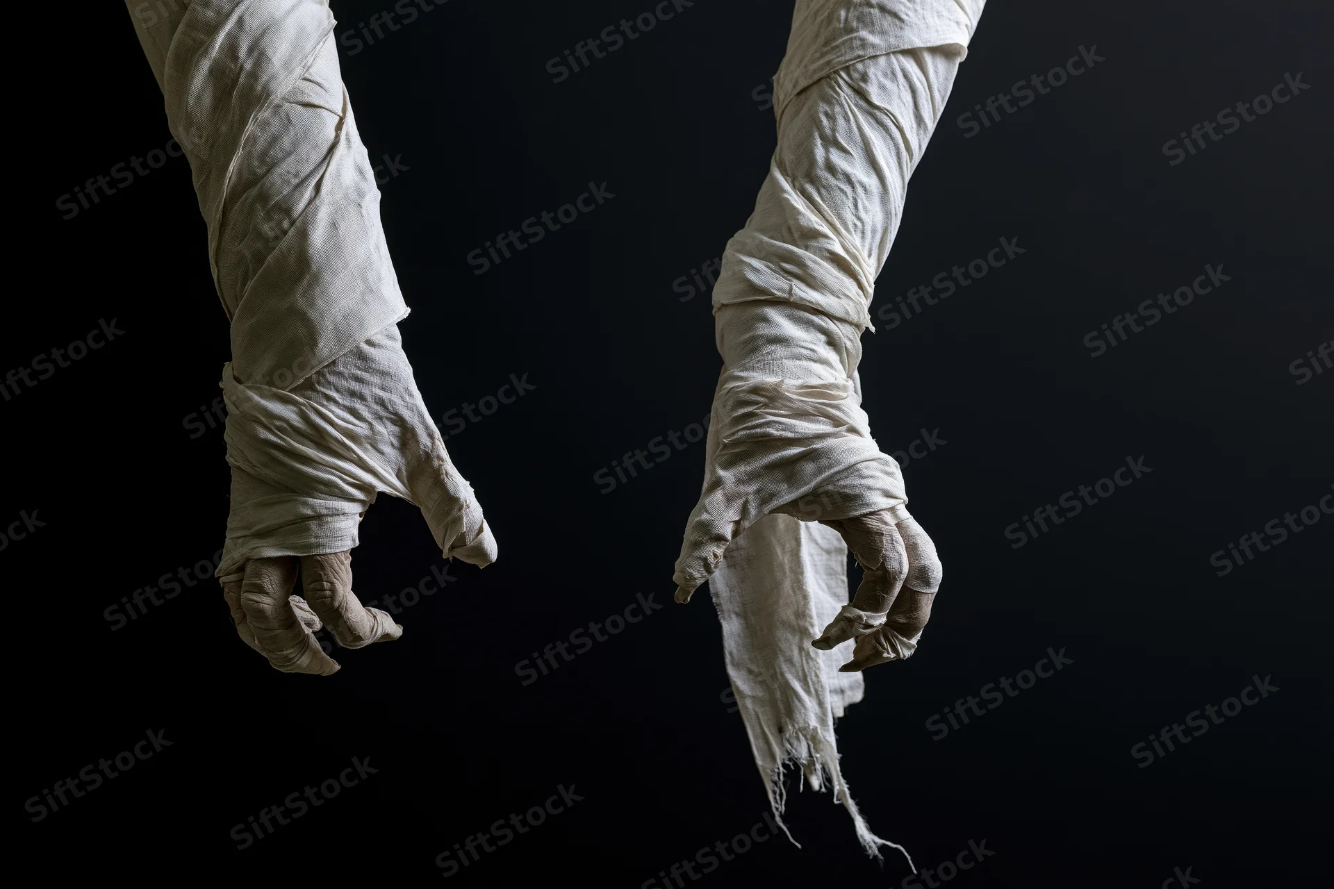 Two mummified hands wrapped in aged linen bandages against a dark background