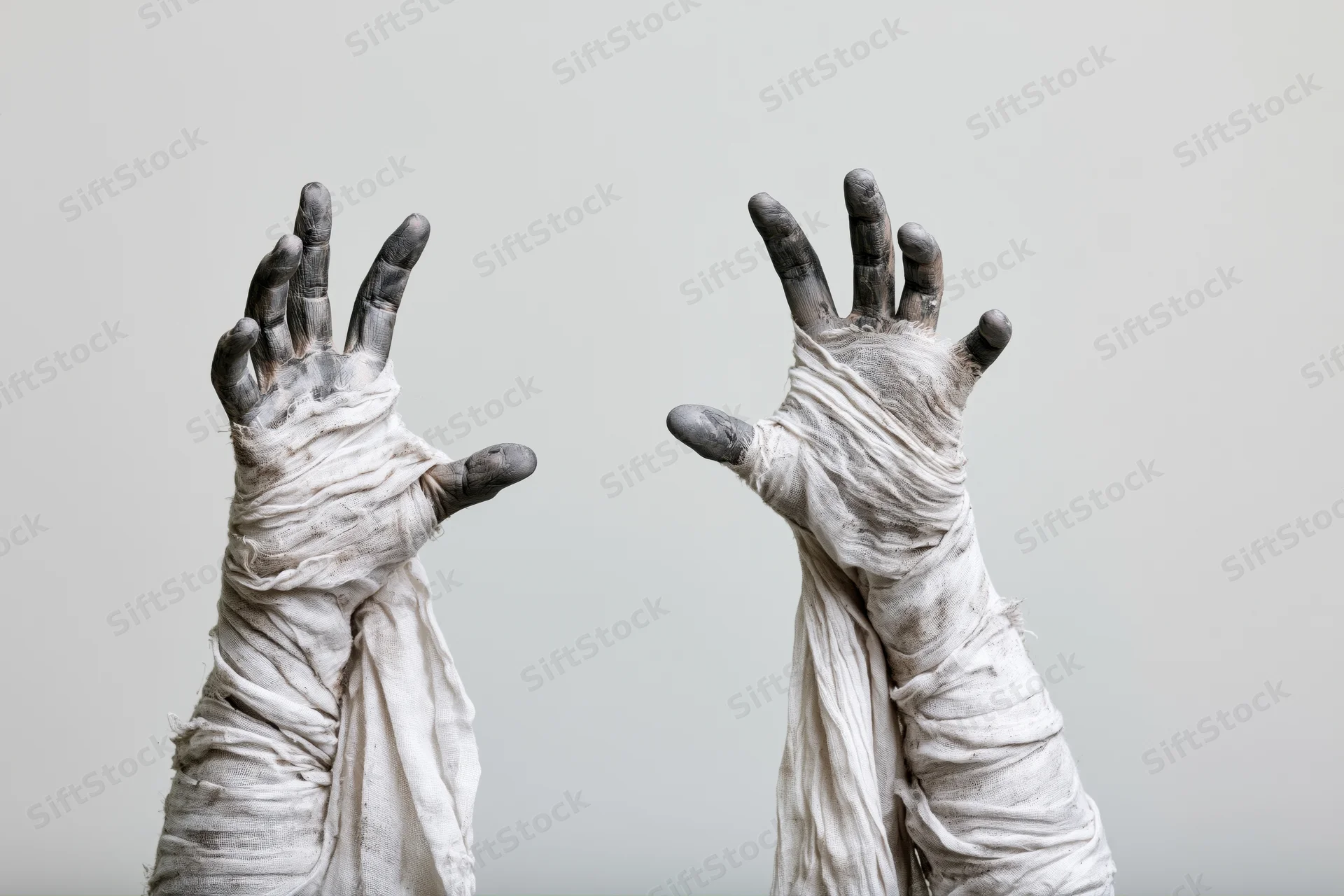 Two wrapped hands raised with fingers spread in a clawing gesture against a plain background
