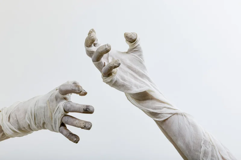 Two bandaged hands reaching toward each other against a white background
