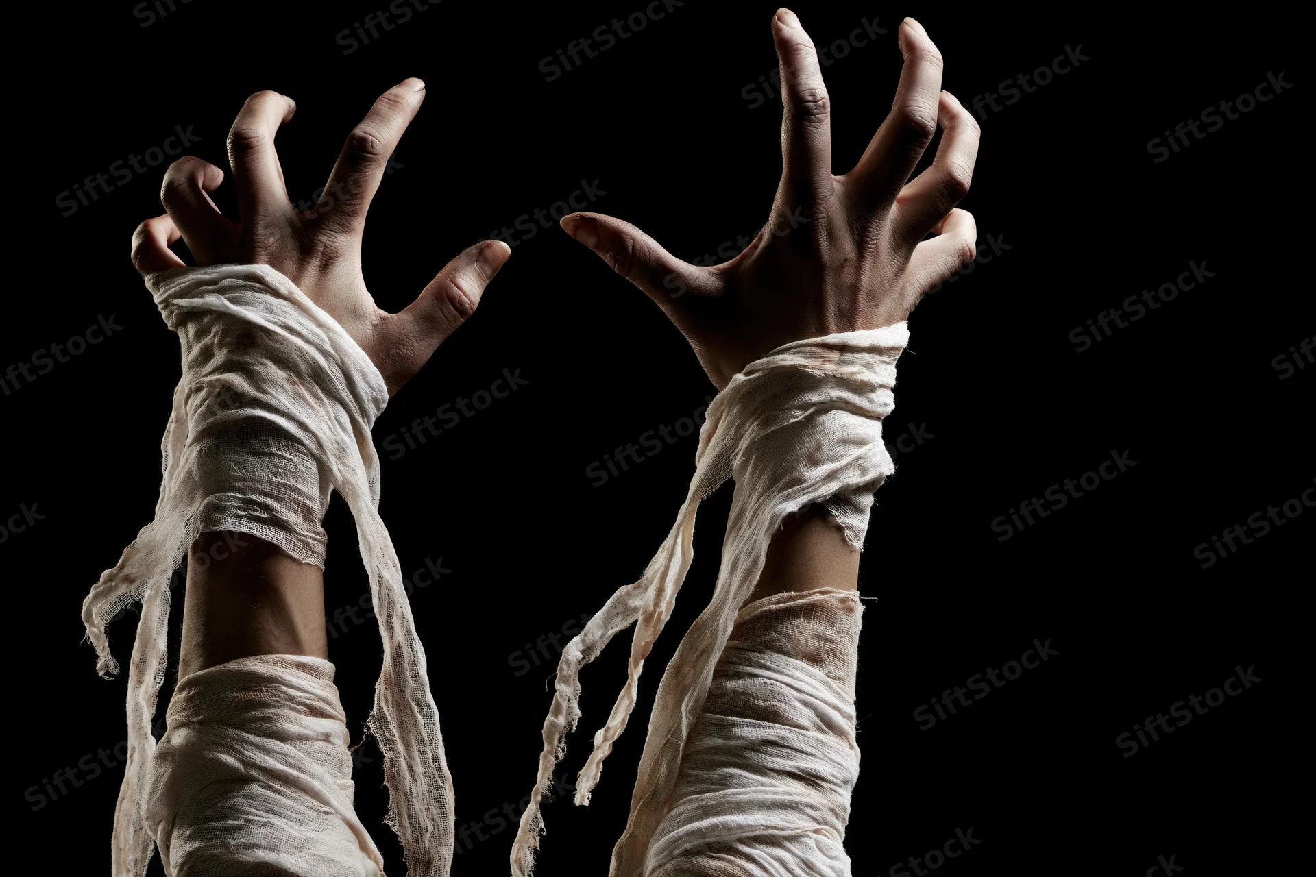 Mummy hands wrapped in tattered bandages reaching upward against black background