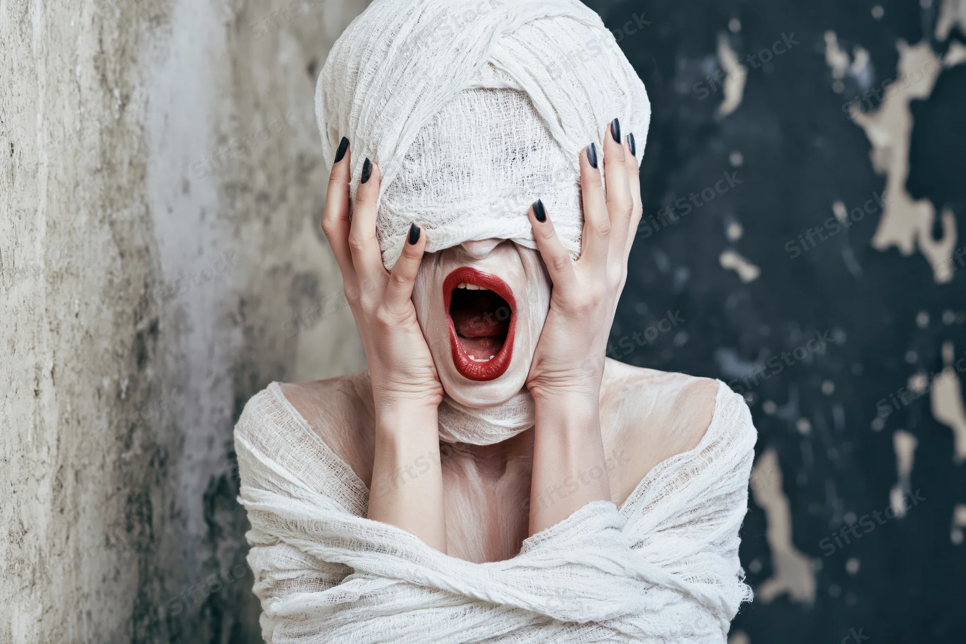 Woman in mummy costume screaming with hands on face against grunge wall