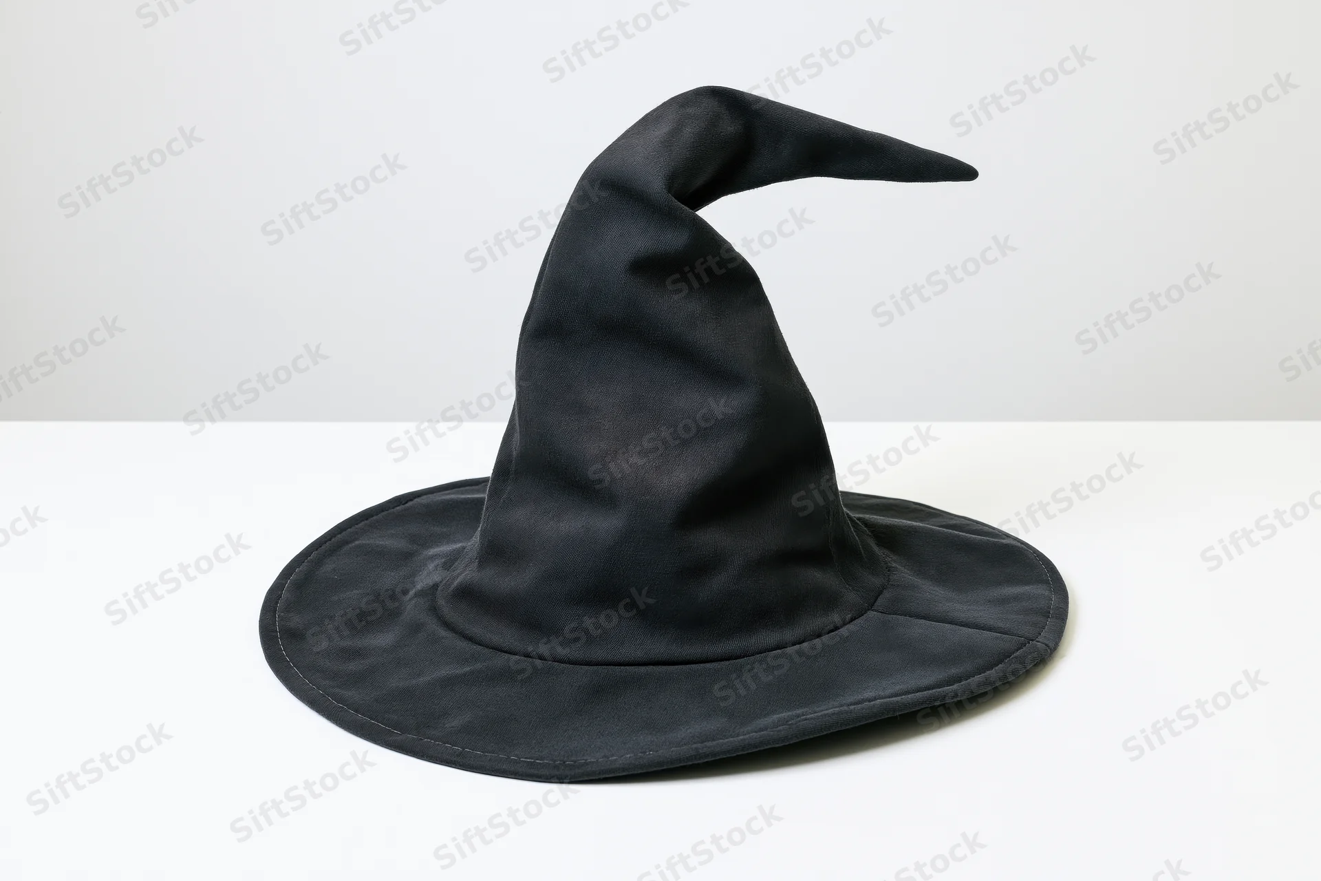 Black witch hat with crooked tip on white surface