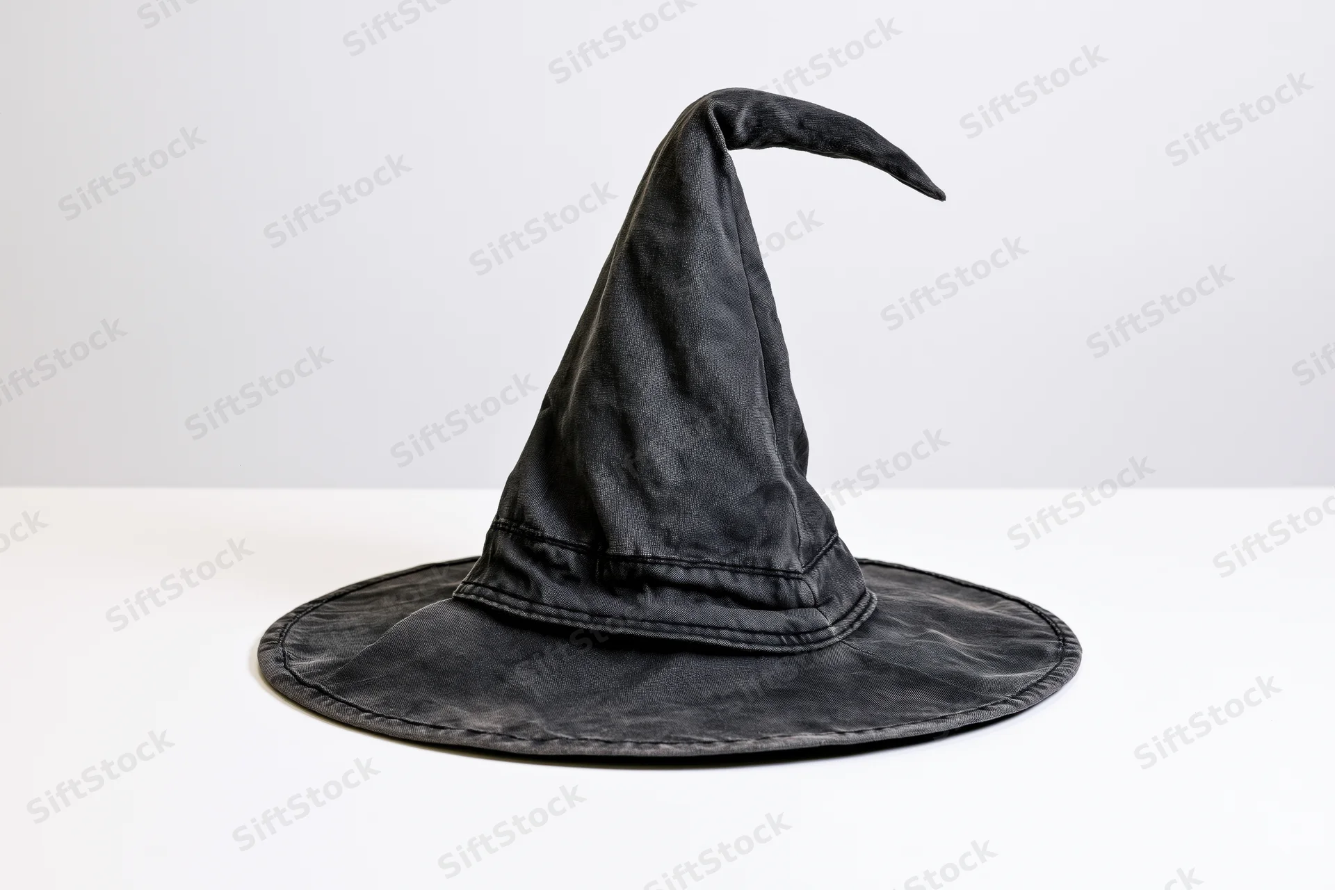 Black witch hat with crooked tip on white surface
