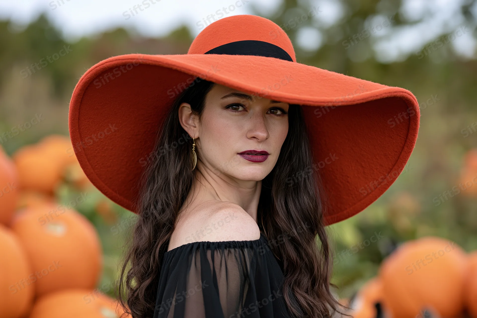 Woman in orange wide-brim hat posing in pumpkin field