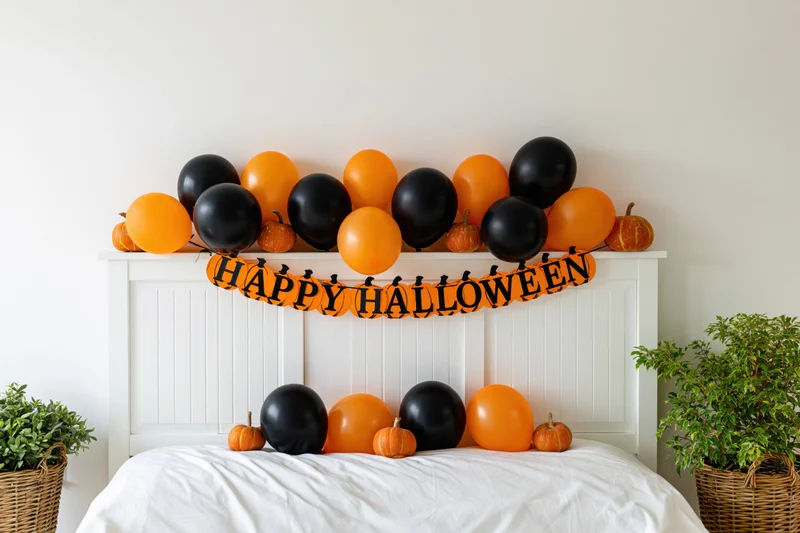 Halloween decorations on a bedroom headboard with orange and black balloons and pumpkins