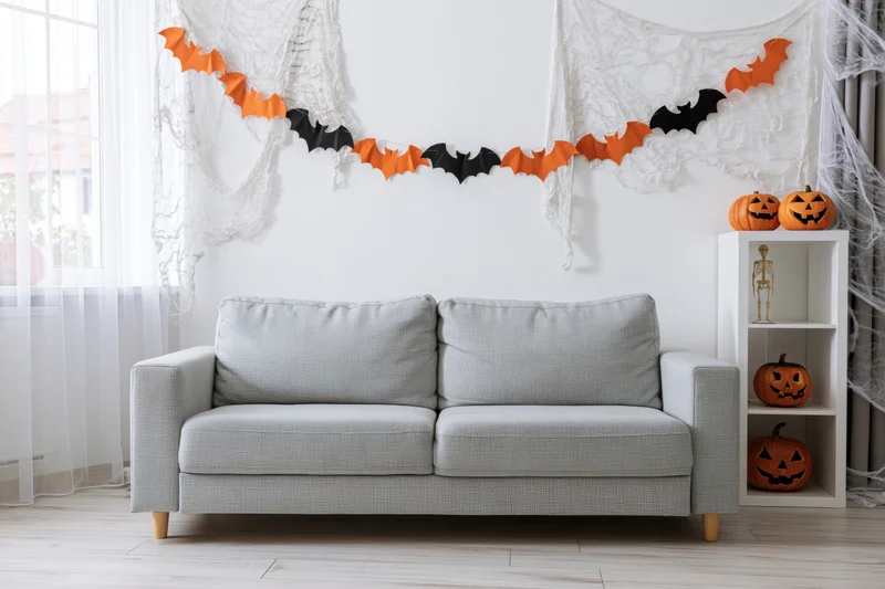 Halloween-decorated living room with light grey sofa and festive decorations on white walls