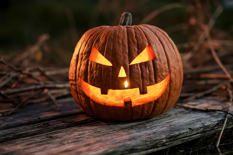 Carved pumpkin glowing with candlelight on wooden surface at night