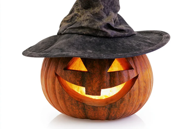 Carved jack-o-lantern with glowing face wearing a dark witch hat on white background