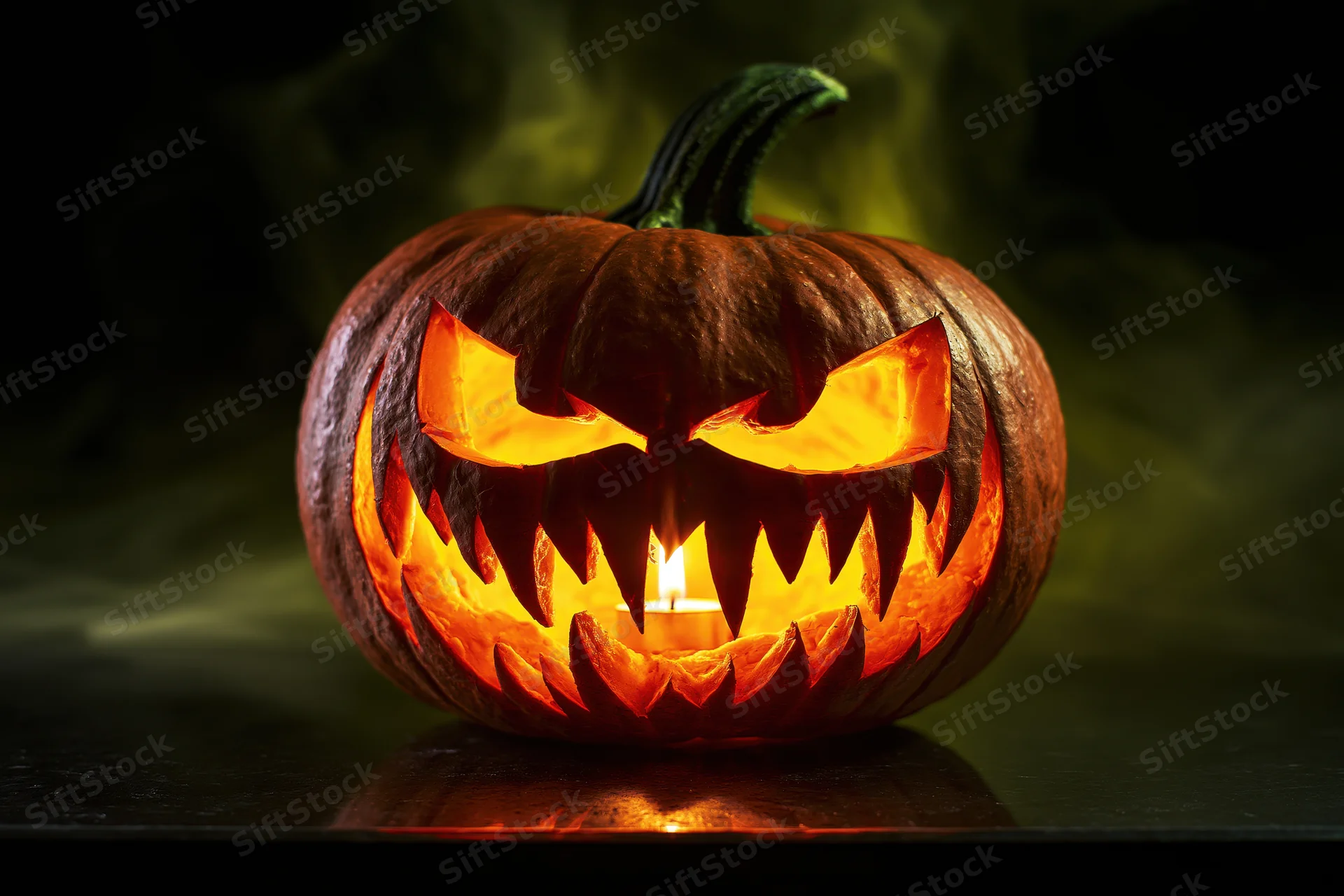 Carved pumpkin with jagged grin lit from within by candle on dark surface with smoke