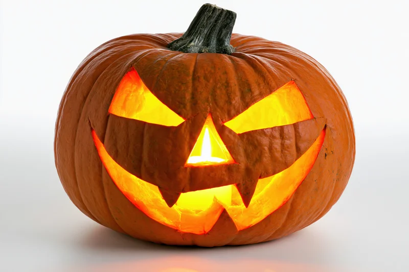 Carved pumpkin with glowing menacing face on white background