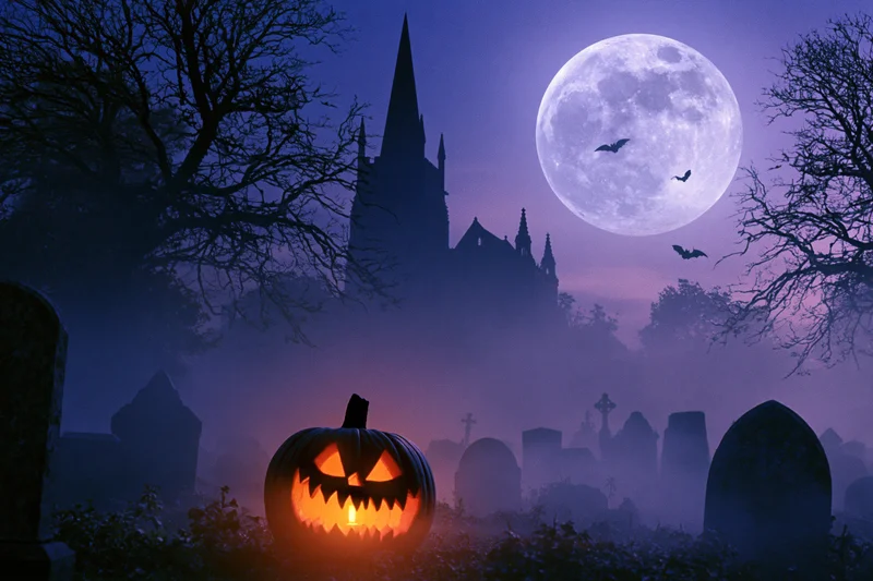 Glowing jack-o-lantern in foggy graveyard with castle and full moon at night