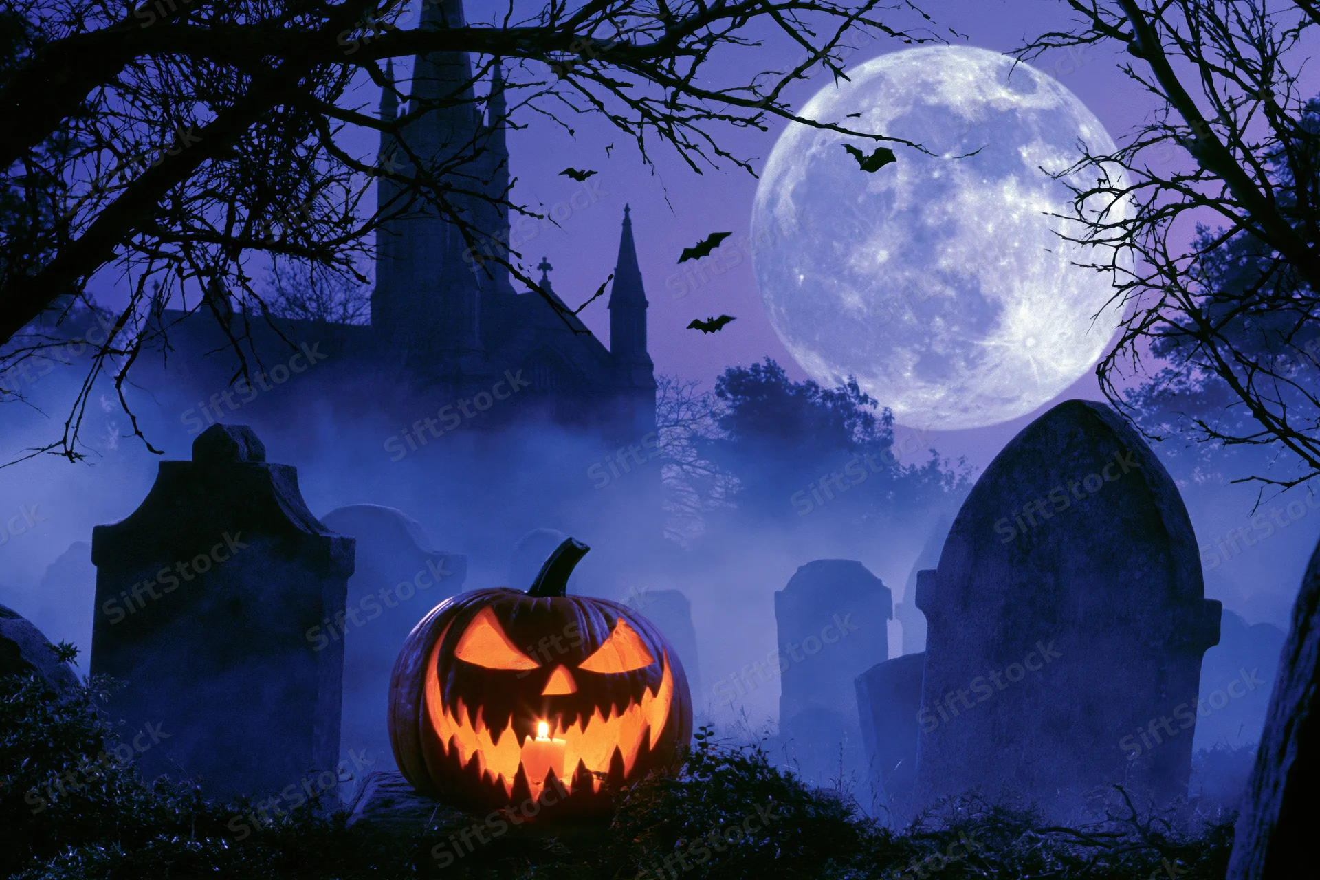 Glowing jack-o-lantern in foggy graveyard at night with full moon and church in background