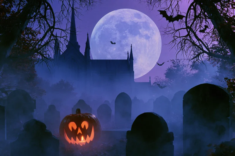 Glowing jack-o-lantern in foggy graveyard at night with full moon and gothic church in background