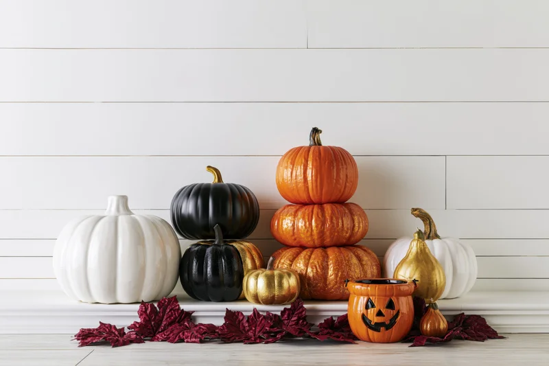 Decorative pumpkins and gourds arranged on a mantel with autumn leaves