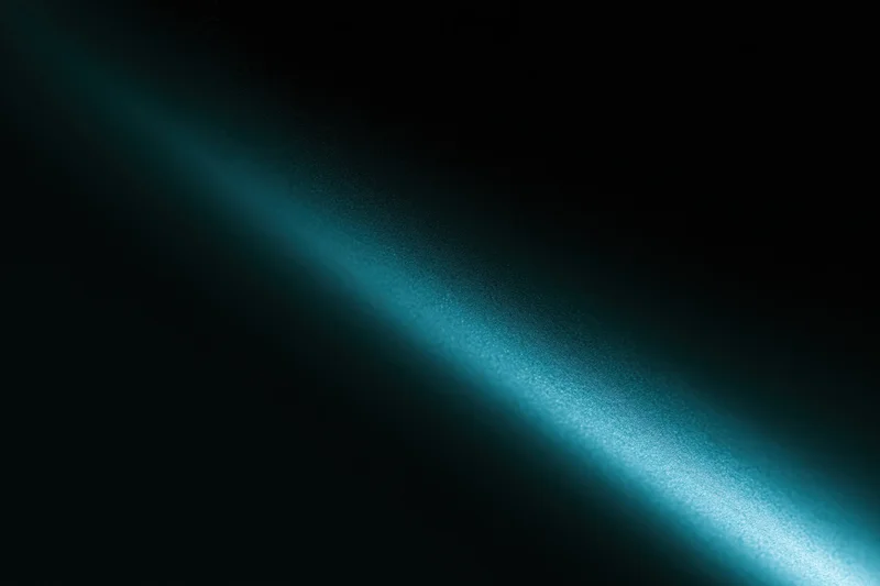 Diagonal beam of soft teal light across dark background