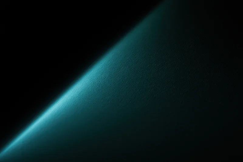 Diagonal band of soft teal-green light cutting across a dark textured surface