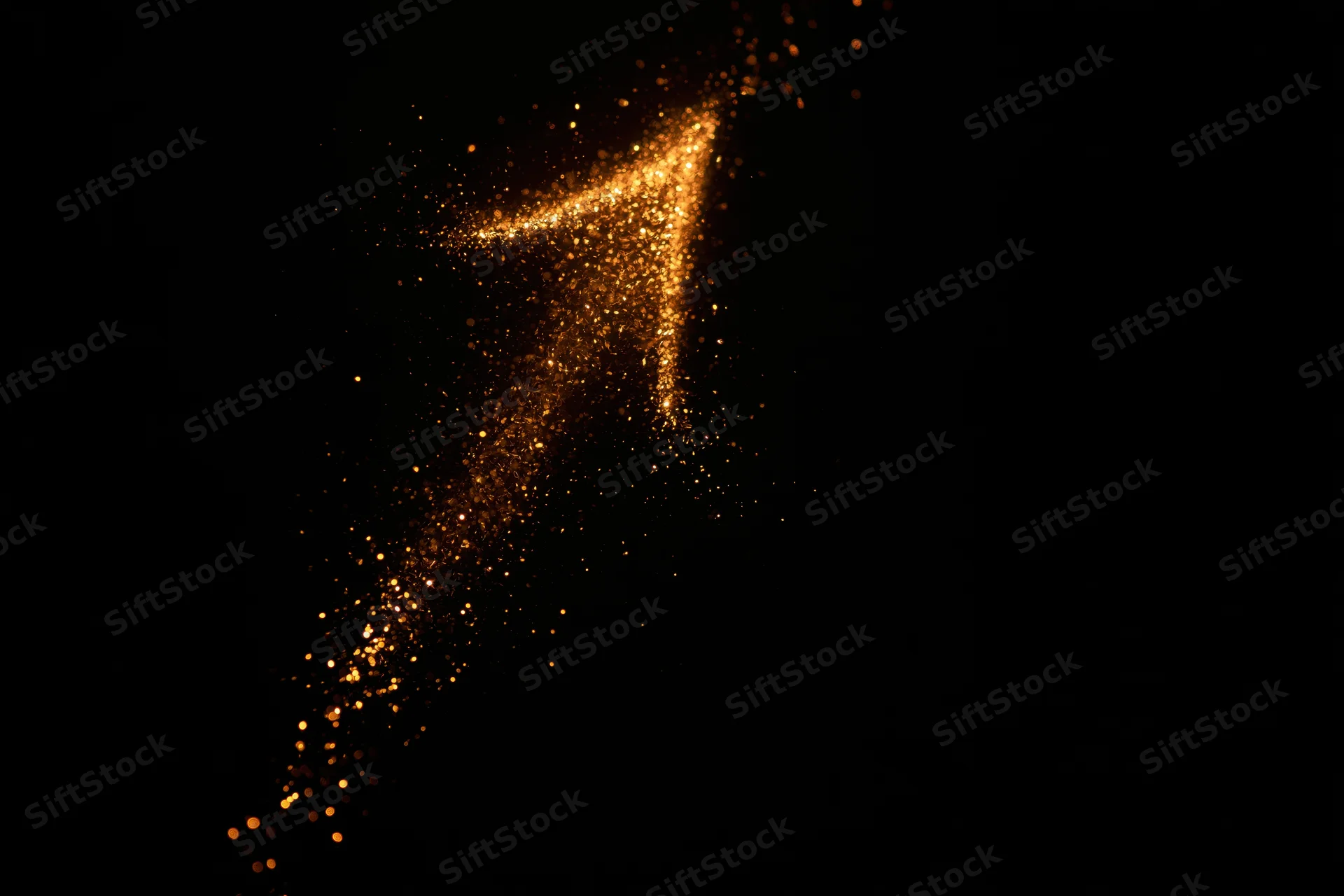 Glowing golden arrow formed from scattered sparks on black background