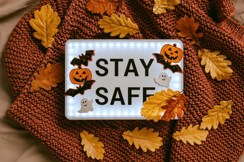 Glowing lightbox with stay safe message and halloween decorations on knitted sweater