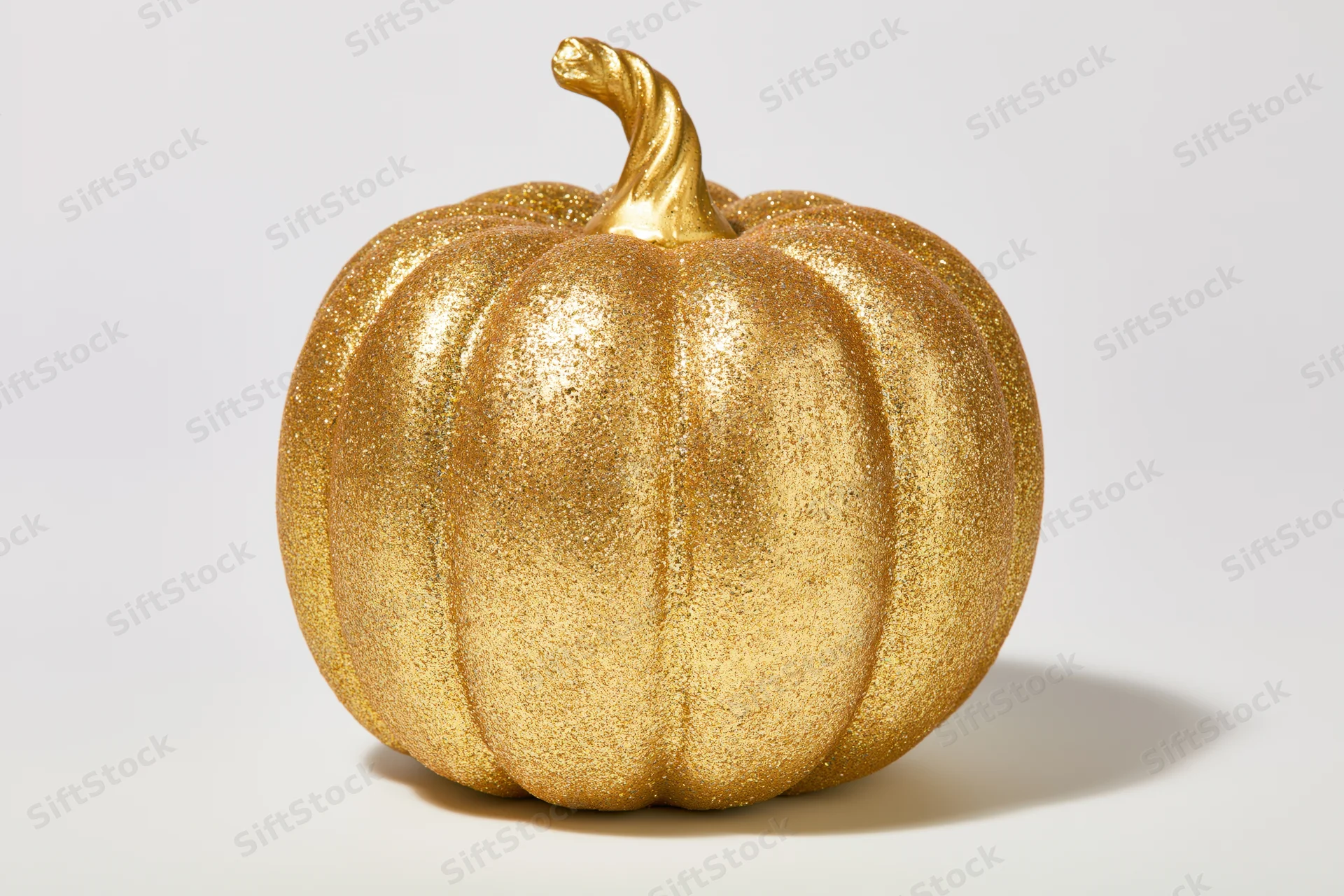 Gold glitter decorative pumpkin on white background with copyspace