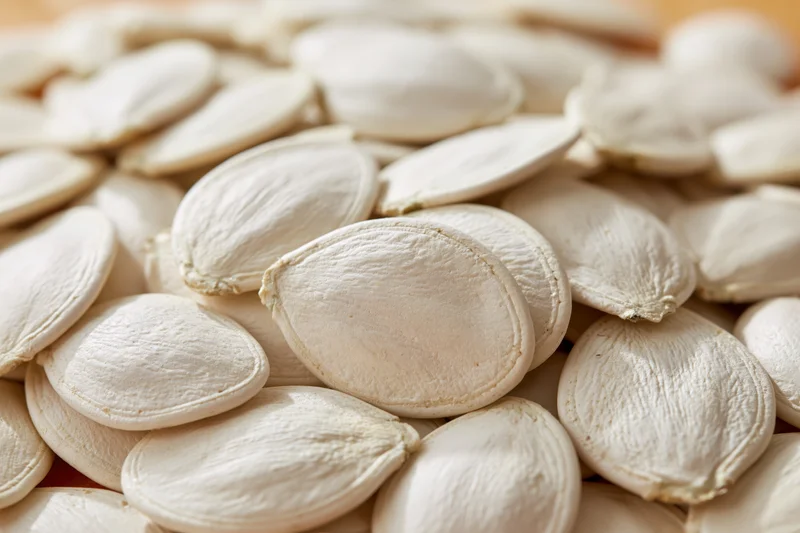 Closeup of raw white pumpkin seeds piled together filling the frame